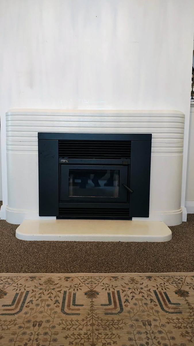 A clean black wood fire insert installed in the white art-deco surround — after Premium Fires