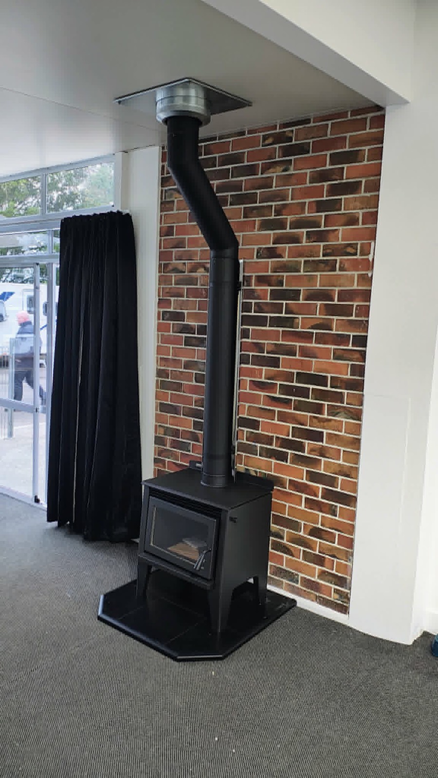 A black freestanding wood fire against a brick feature wall