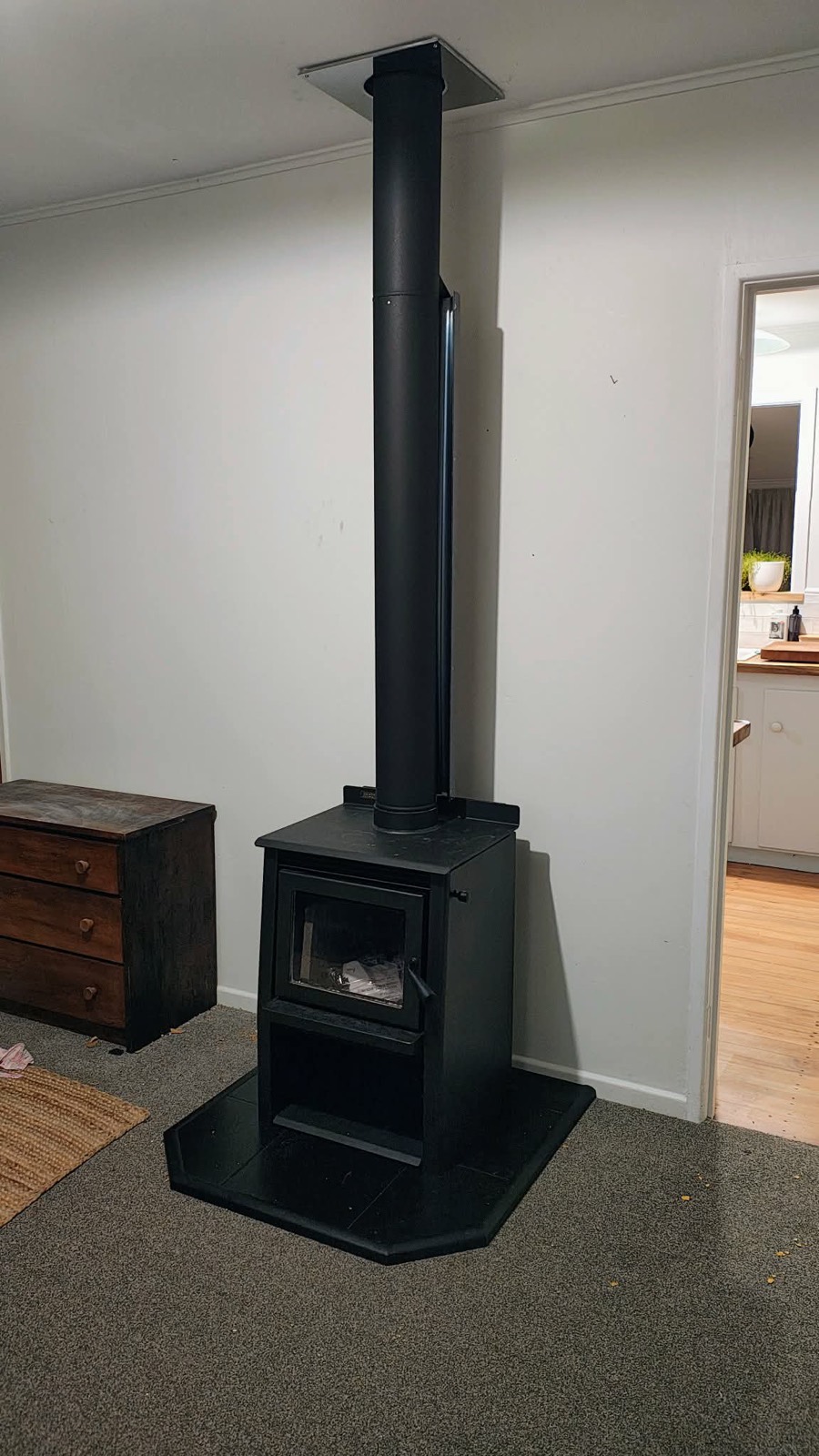 A black freestanding wood fire with a tall flue installed in a Northland lounge