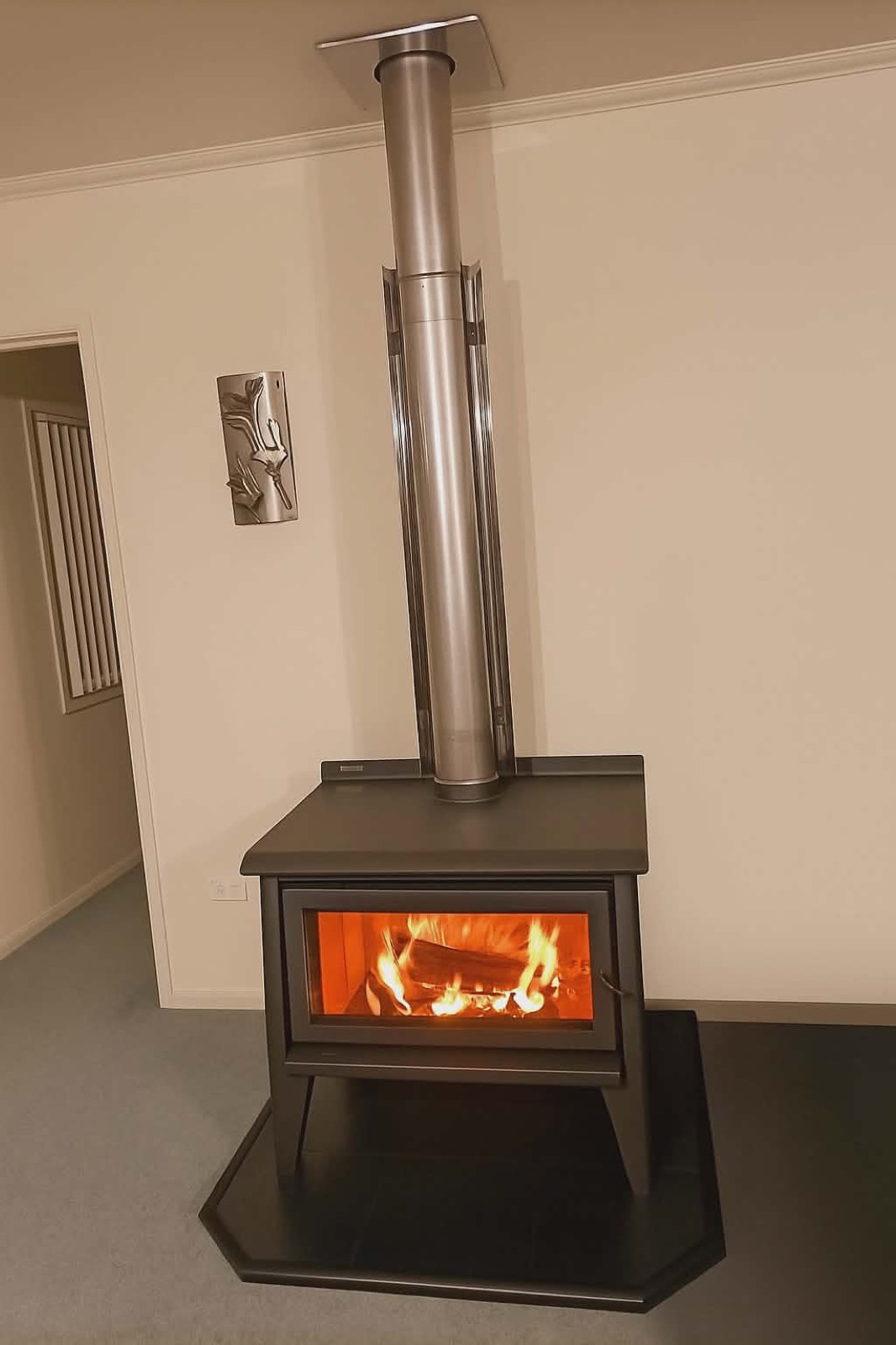A modern grey freestanding wood fire burning in a Northland living room