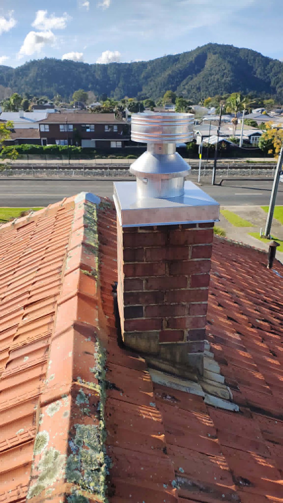 A stainless chimney cap on a brick chimney over a tiled Whangarei roof