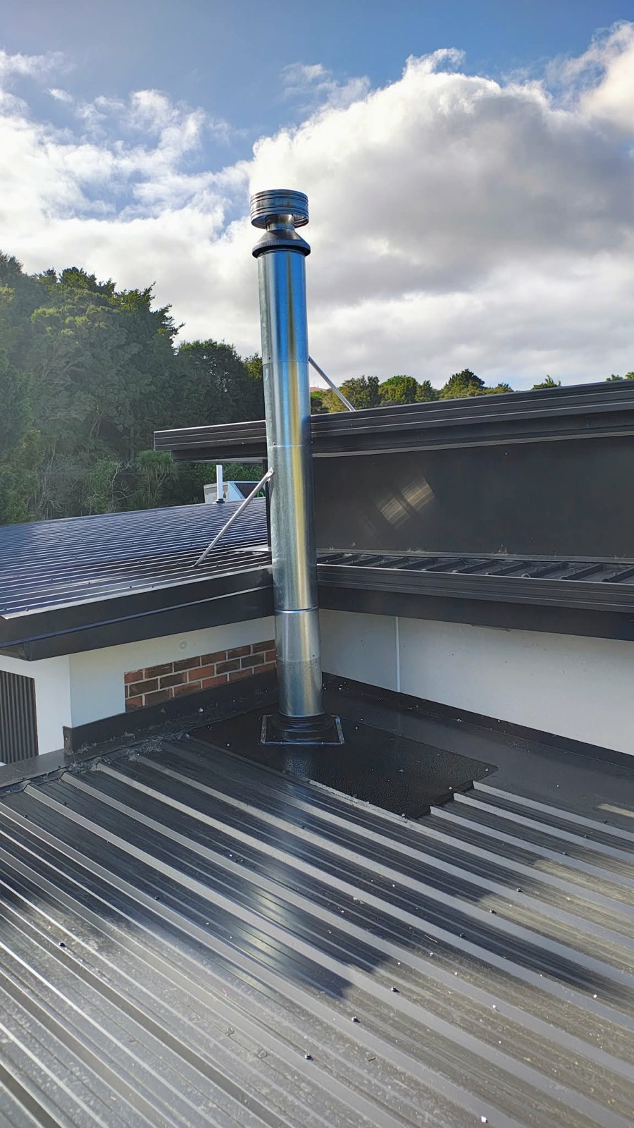 A new galvanised stainless flue installed through a metal roof in Northland
