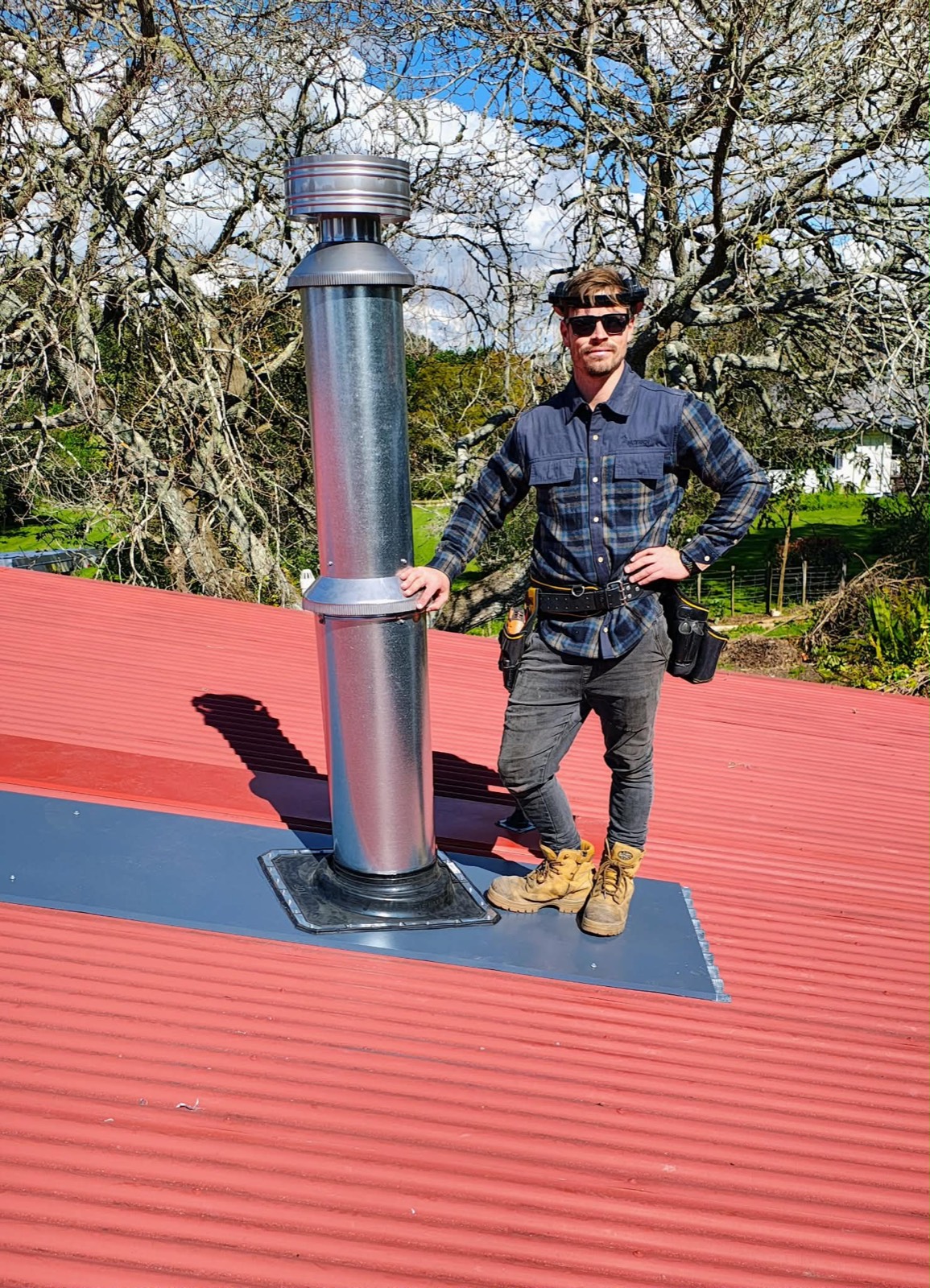 Luke of Premium Fires standing beside a newly installed flue on a roof